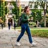 Young woman in comfortable casual outfit walking across university campus quad in natural daylight