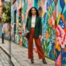 Woman wearing complete styled concert outfit posed against vibrant painted street mural background