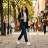 Woman walking confidently on city sidewalk in effortlessly chic outfit with soft natural lighting