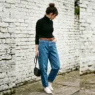 Woman in high-waisted baggy jeans with fitted black turtleneck and brown belt showing balanced proportions