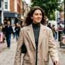 Woman wearing neutral acubi outfit with oversized blazer walking on city sidewalk in natural light