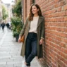 Woman in casual everyday outfit leaning against red brick wall in soft daylight