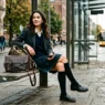 Woman in casual school outfit sitting on bench with handbag in urban setting