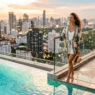 Woman in elegant summer coverup by rooftop pool with Miami skyline and turquoise water backdrop