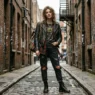 Woman in a complete grunge outfit posed in a warm brick alley with soft overcast light and shallow depth of field
